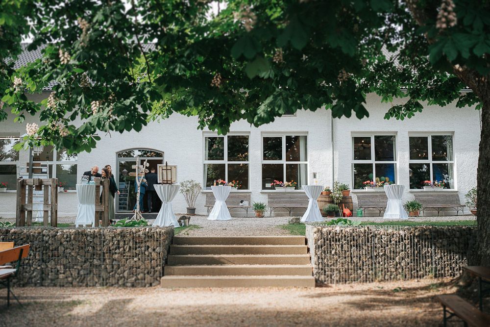 White wedding ceremony setup with chairs on stone porch steps of historic building with garden ambiance.