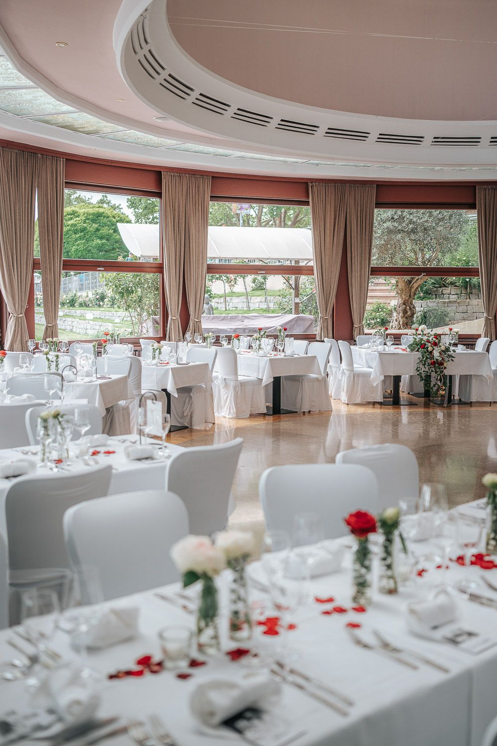 Elegant banquet hall with circular windows, white tablecloths, and floral centerpieces set for a formal dining event.