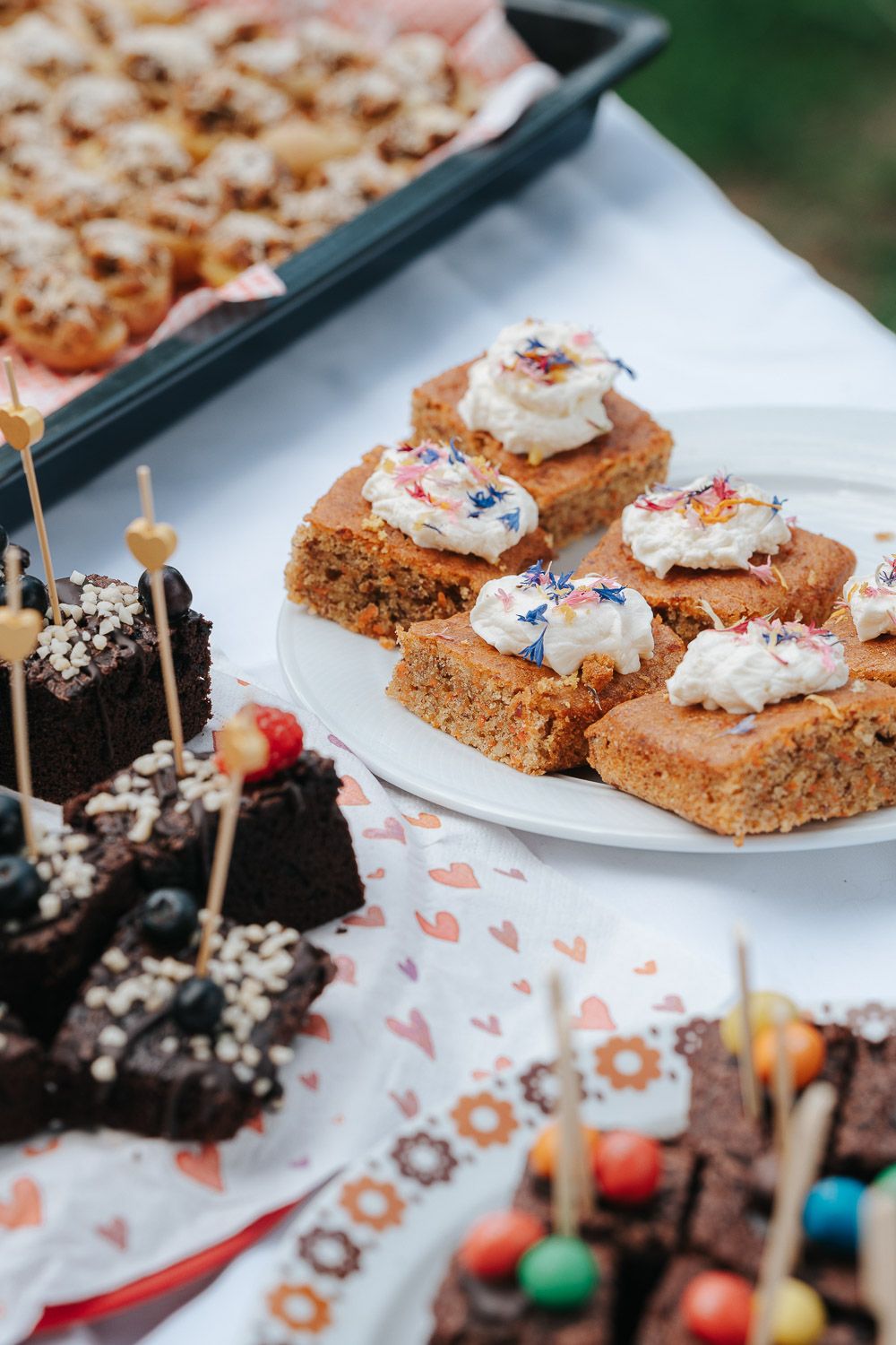 Homemade blonde brownies topped with creamy frosting and colorful decorations on a white serving plate.