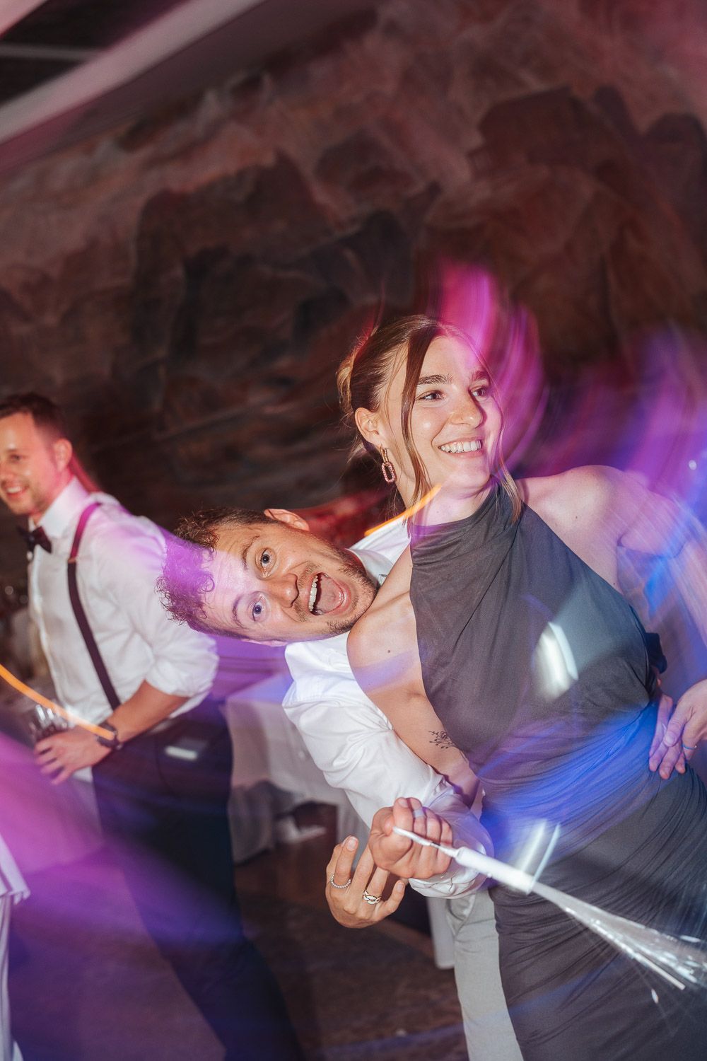 Joyful dancers on a colorful illuminated dance floor under purple and blue lights at a celebration.