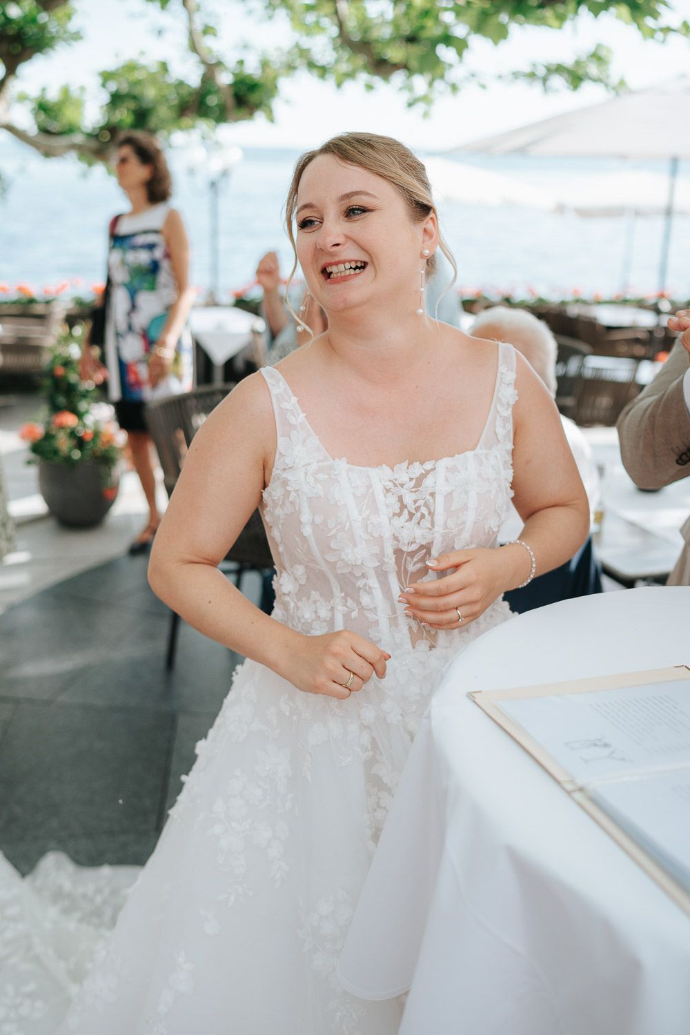 A close-up sequence of a bride in a white lace wedding dress laughing and smiling at an outdoor reception.