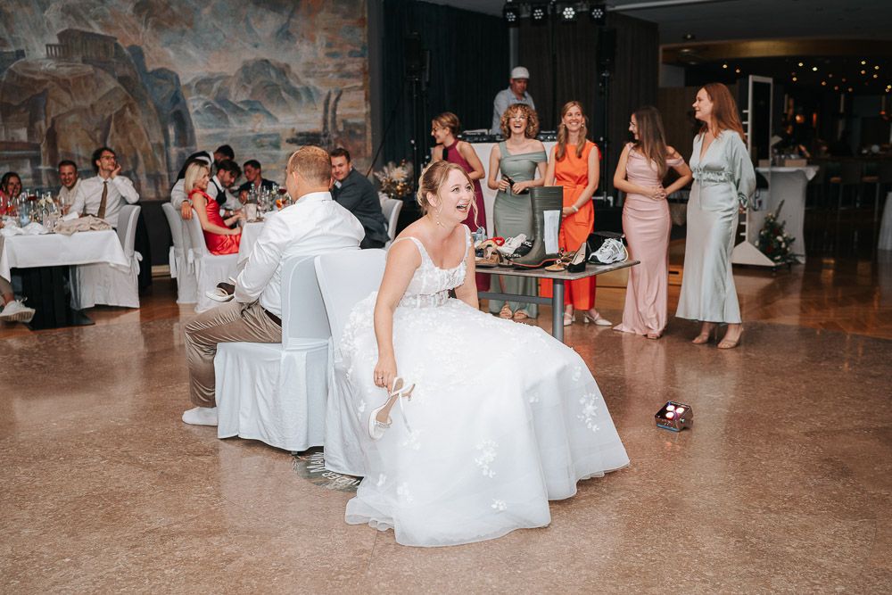Wedding reception party guests watch as someone removes a garter at a reception in a banquet hall.