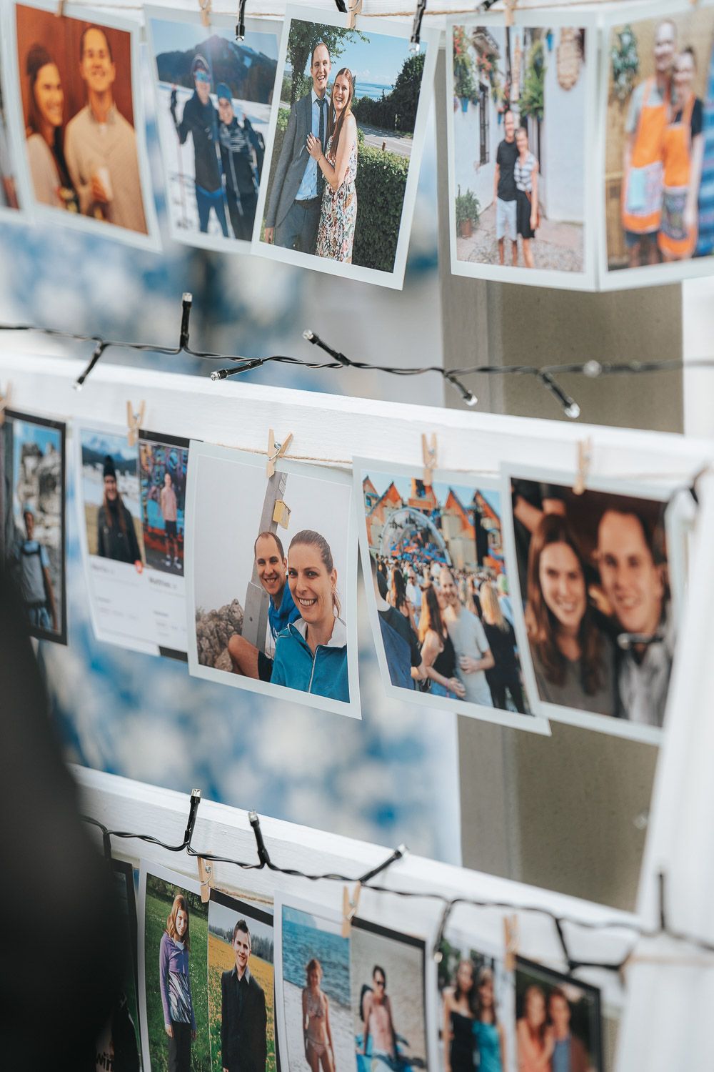 Multiple personal photographs strung up on string lights against a white wall create a cozy memory display.