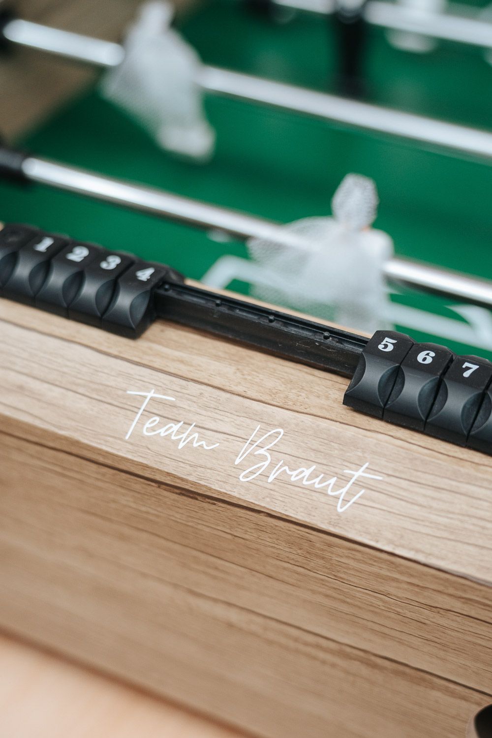 Close-up view of a foosball table handle and white players against a green playing field.
