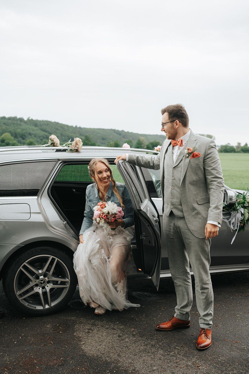 A couple shares a candid moment outside a black limousine during their wedding photo shoot.