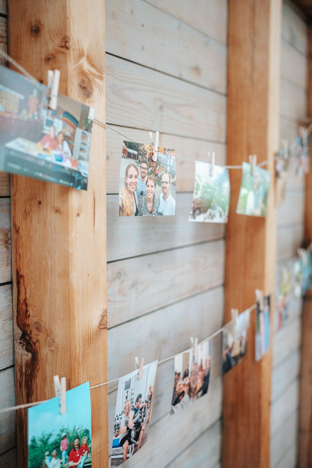 Polaroid photographs hung on twine with wooden clothespins against a rustic wooden wall display.