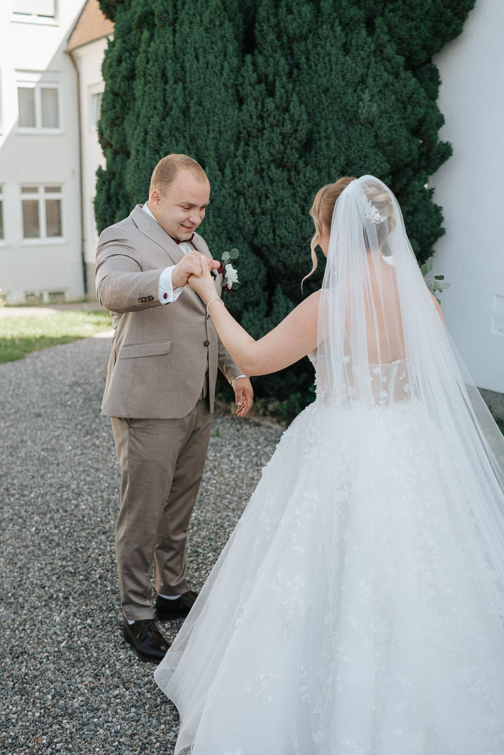 A romantic wedding couple shares an intimate moment together in front of lush green cypress trees.