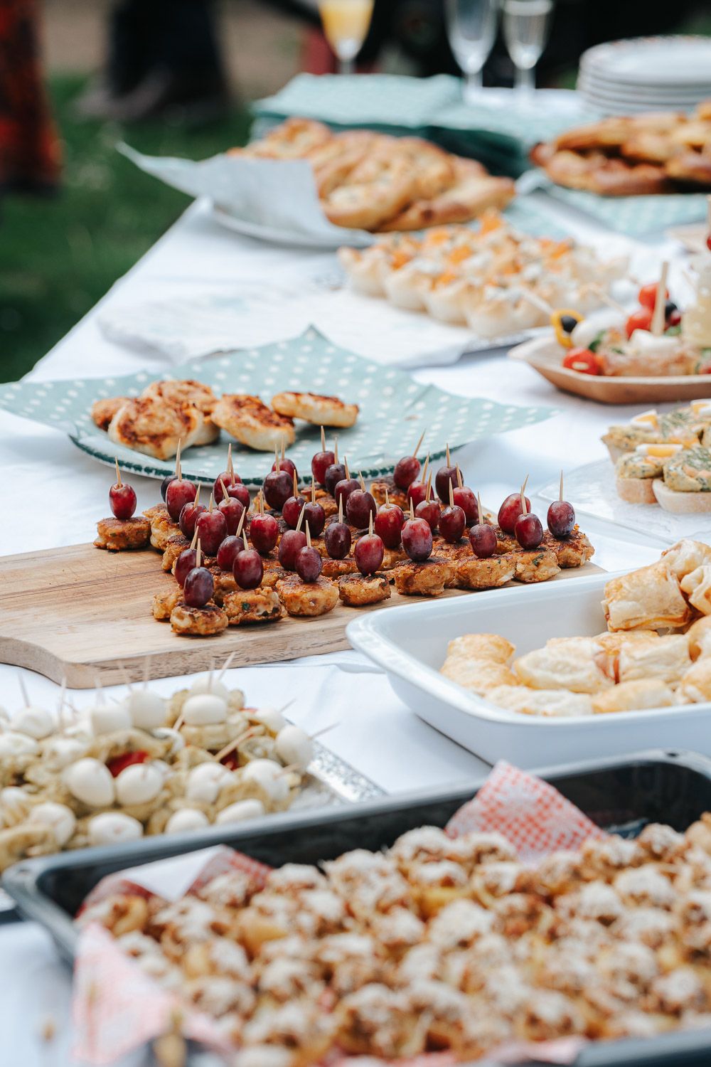Catering display featuring rows of elegant appetizers and canapes with various toppings on white serving platters.
