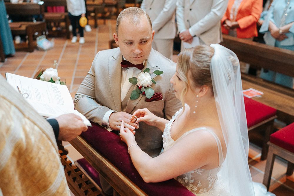A tender moment during a wedding ceremony as the couple exchanges rings at the altar in a church.