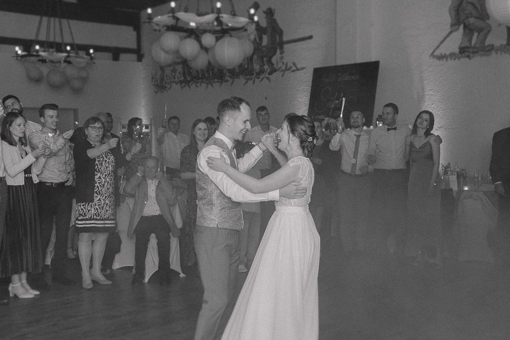 A couple shares their first dance at a wedding reception as guests look on in this vintage black and white photograph.