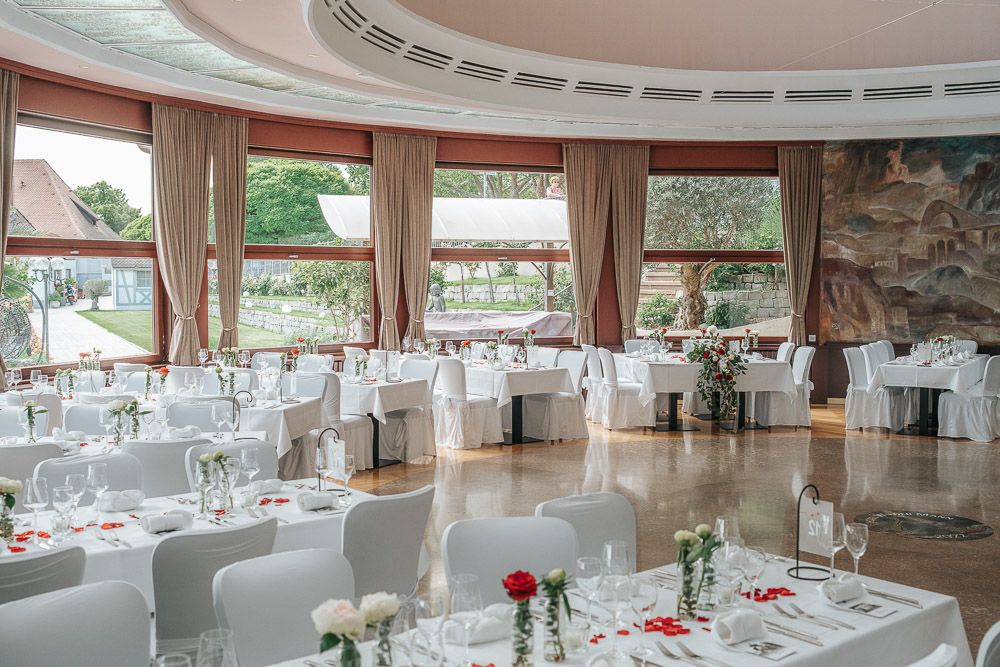 Elegant banquet hall with circular layout features white-clothed tables and chairs set for a formal dining event.