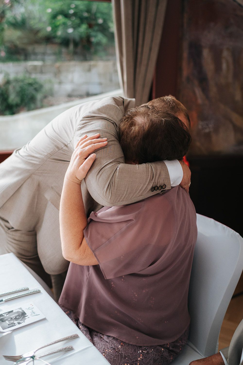 Person in white jacket resting their head on a brown surface at a dining table in repeated sequence of similar poses.