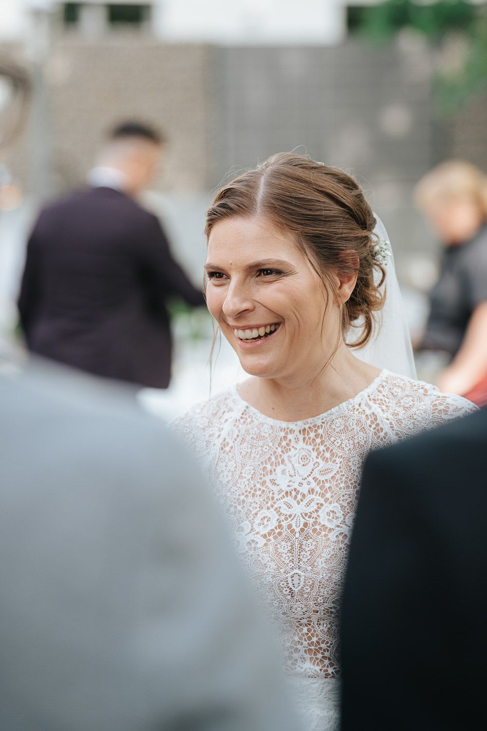 A series of candid wedding photos showing a bride in a white lace dress smiling during an outdoor ceremony.