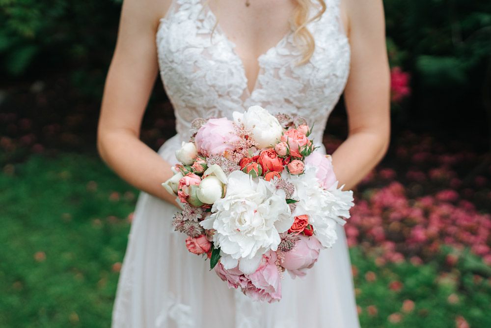 A close-up view of someone holding a delicate pink and white floral wedding bouquet.