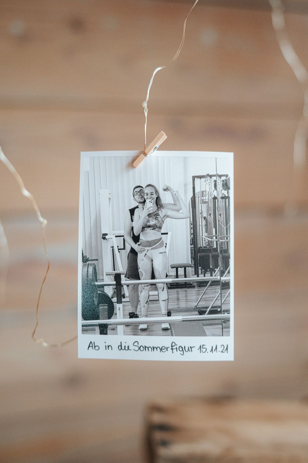 Black and white polaroid photo clipped to string showing a casual summer boating scene.