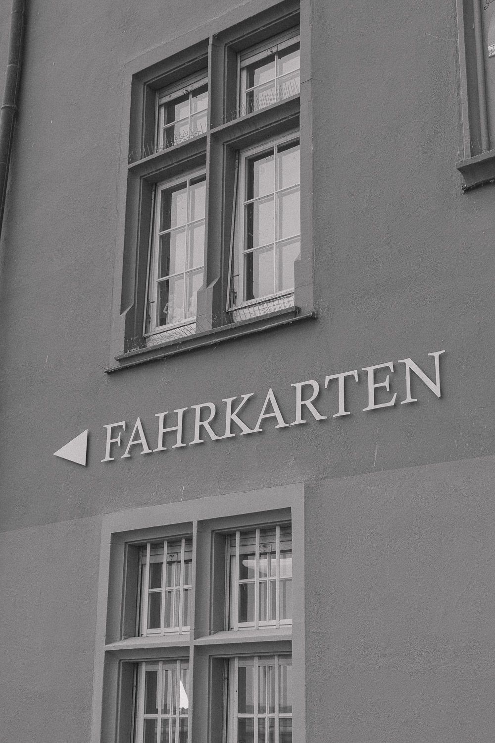 Black and white photograph of windows on a building with German text 'FAHRKARTEN' and an arrow sign.