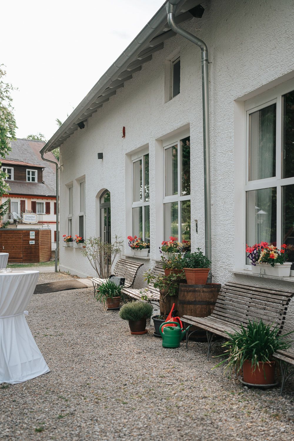 White-walled porch with wooden benches, flowerpots, and gravel courtyard showcases modern minimalist outdoor living space.
