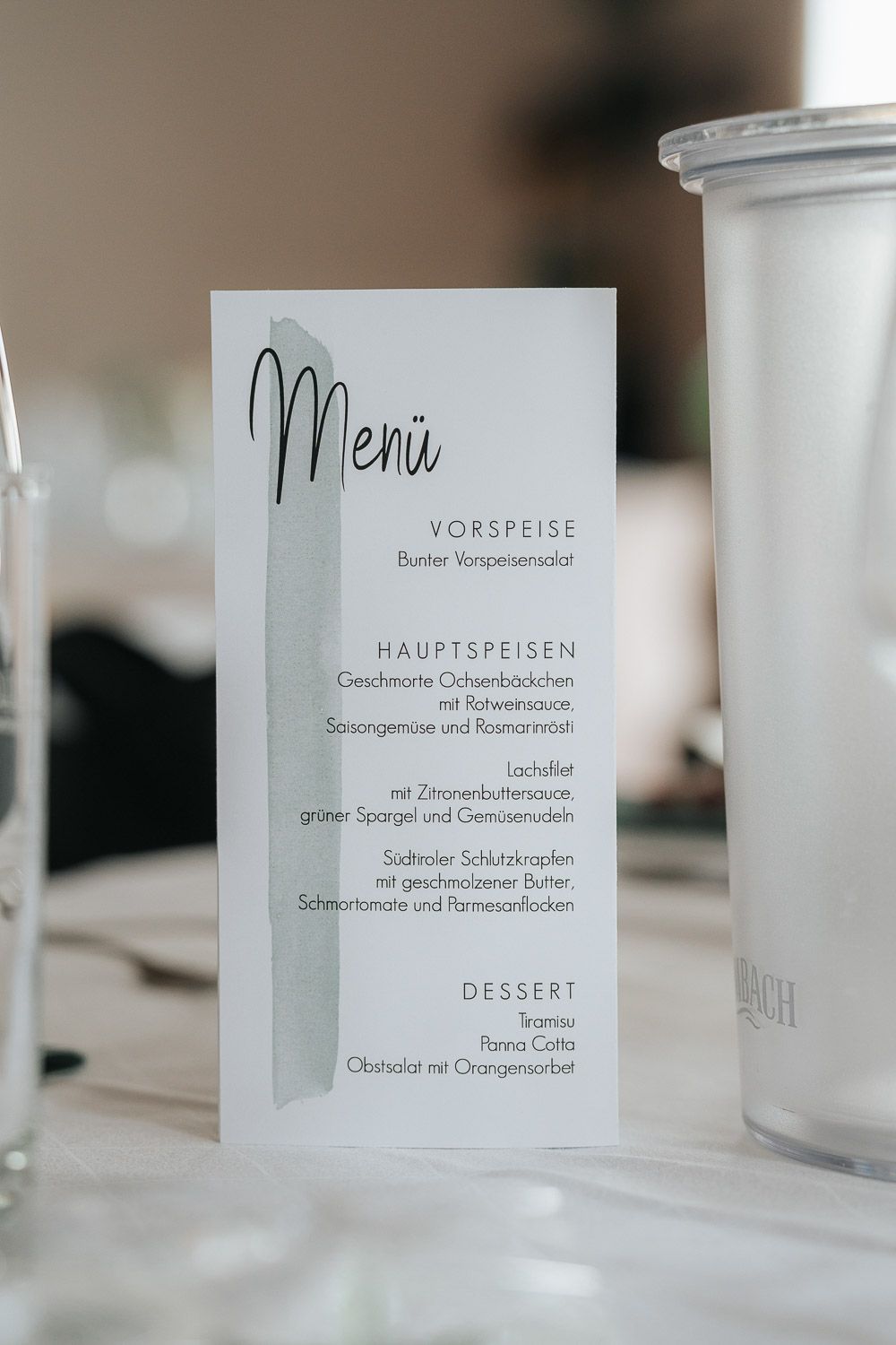 An elegant menu card in white and black lettering displays Vorspeise, Hauptspeisen and Dessert courses for a formal dinner.