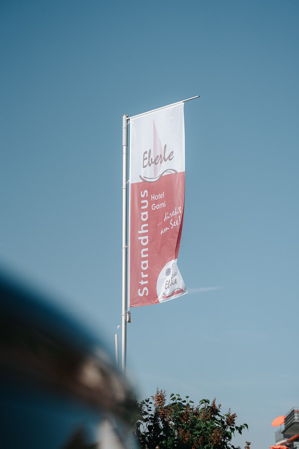 A series of minimalist white fabric banners with red designs fluttering against a blue sky.