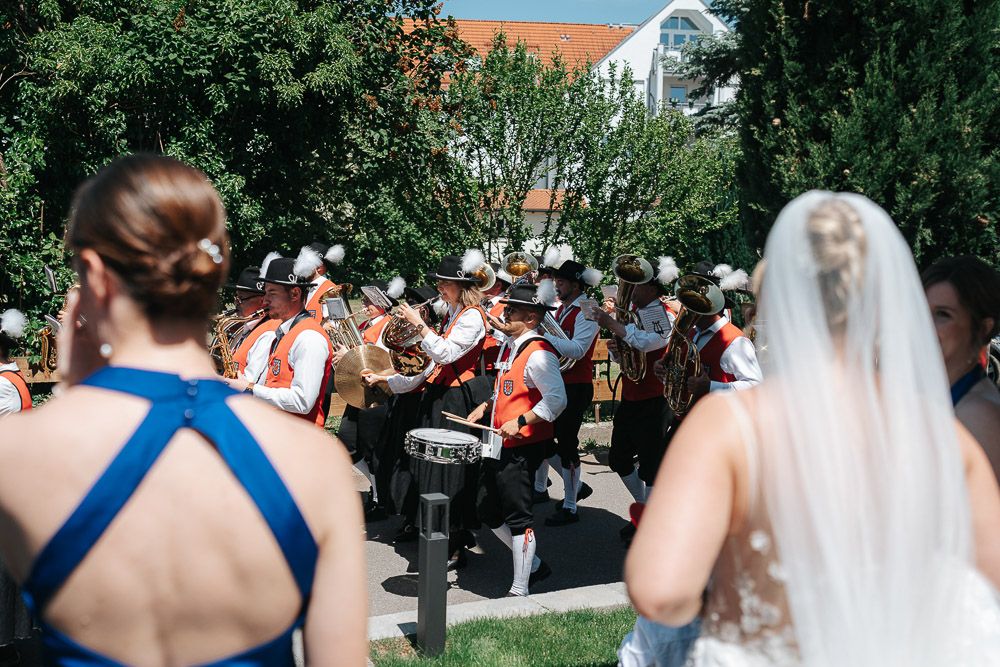 Bride and wedding guests enjoying outdoor reception celebration at garden venue during daytime festivities.