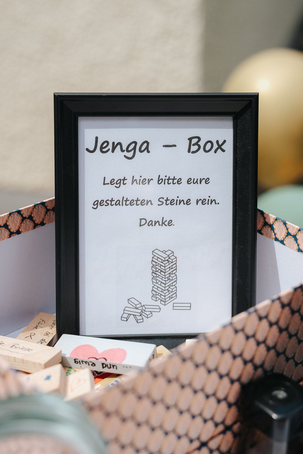 A collection of signs and instructions for a guest book made using Jenga blocks displayed on patterned surfaces.