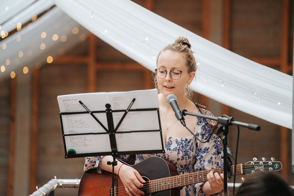Musicians perform together on stage with sheet music stands and guitars, creating a collaborative musical atmosphere.