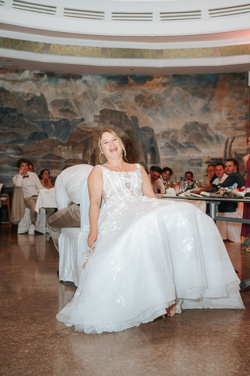 A bride in a flowing white ballgown twirls on the dance floor during a wedding reception in an elegant venue.