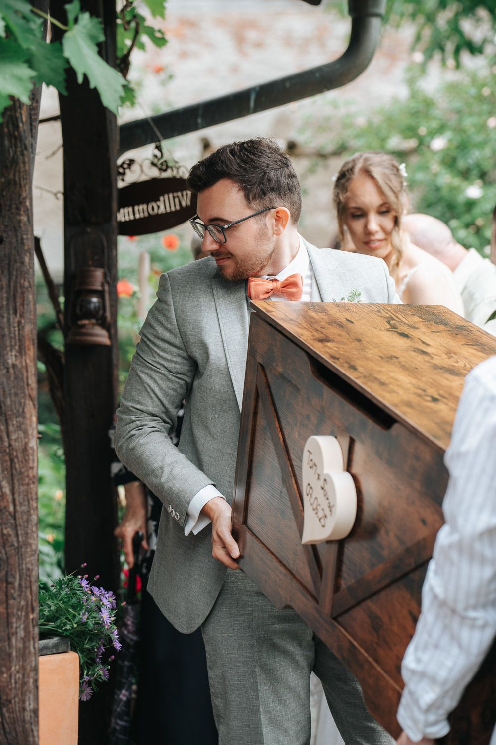 Couple sharing a joyful moment at an outdoor wedding venue decorated with greenery and rustic wooden details.