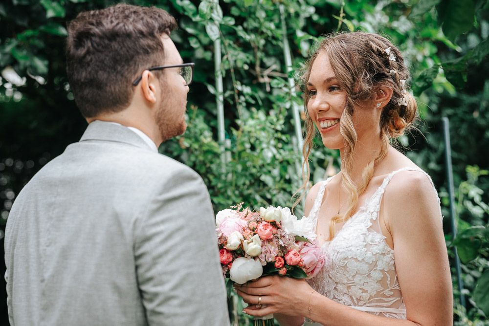 Bride and groom share a joyful moment together in a lush green garden setting during their wedding celebration.