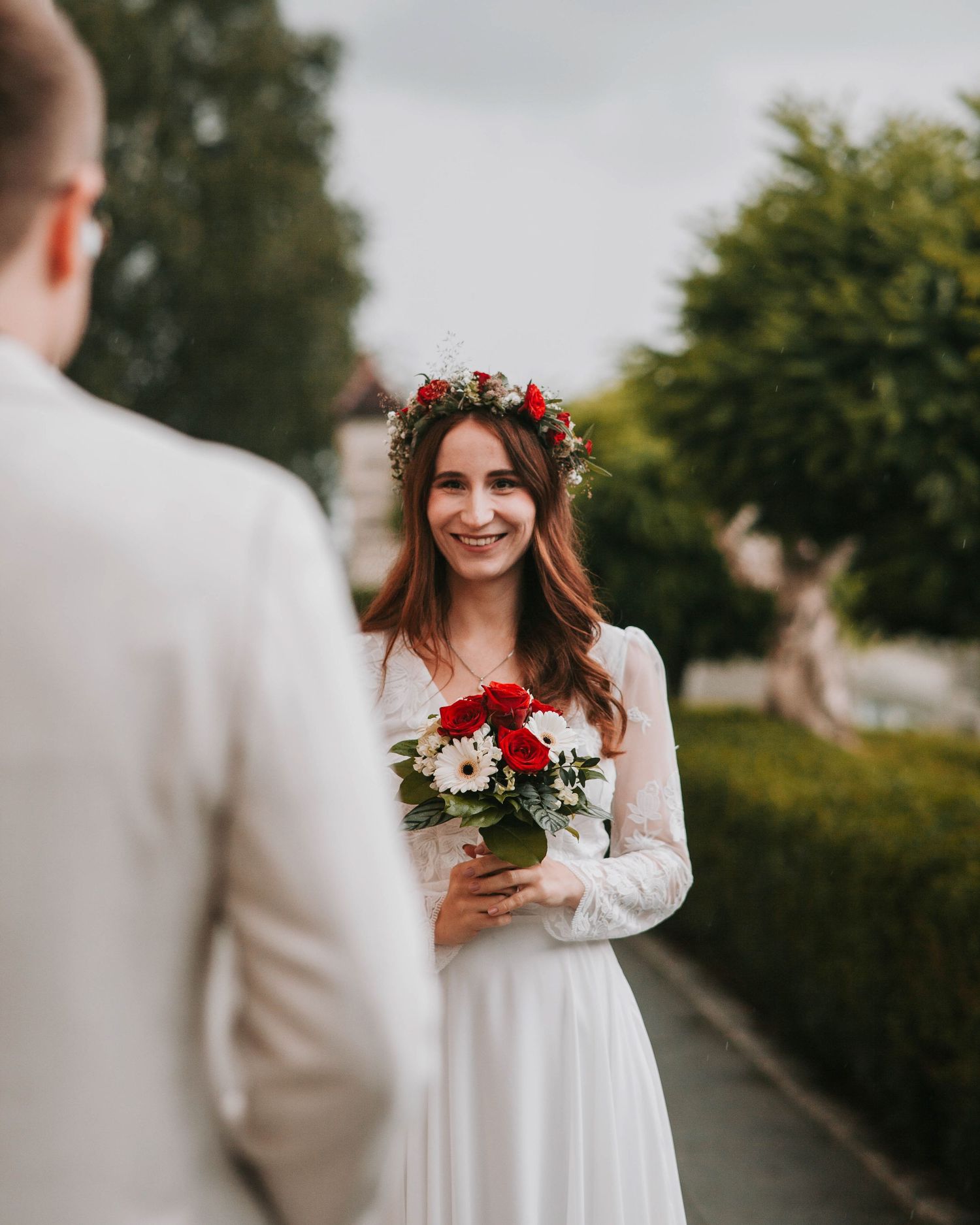 Romantic wedding couple in white attire share intimate moments in a garden setting during golden hour.