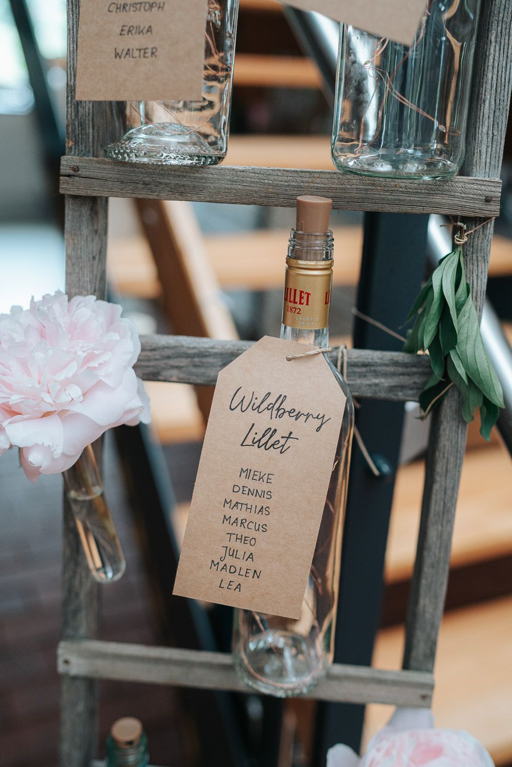 Rustic wooden shelf display with pink flowers and drink menu tag showing 'Wildberry bliss' cocktail list.