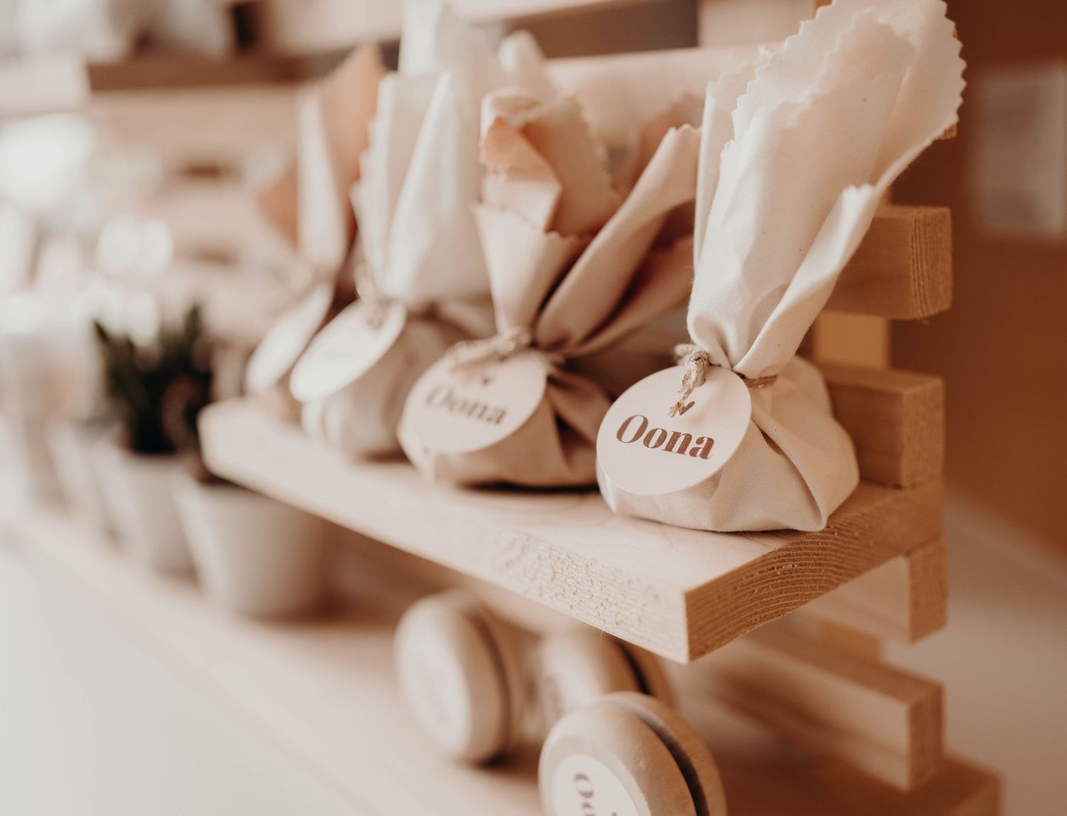Small paper gift bags arranged on wooden shelves in soft beige tones.