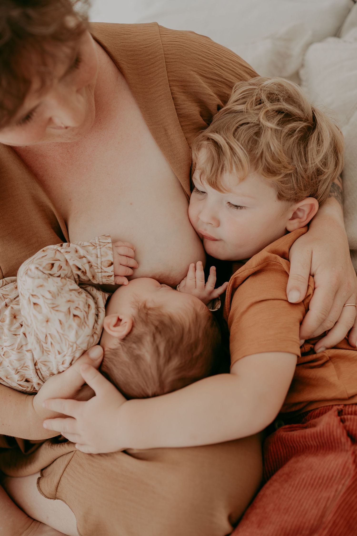 Tender moment of siblings bonding with newborn during feeding time.