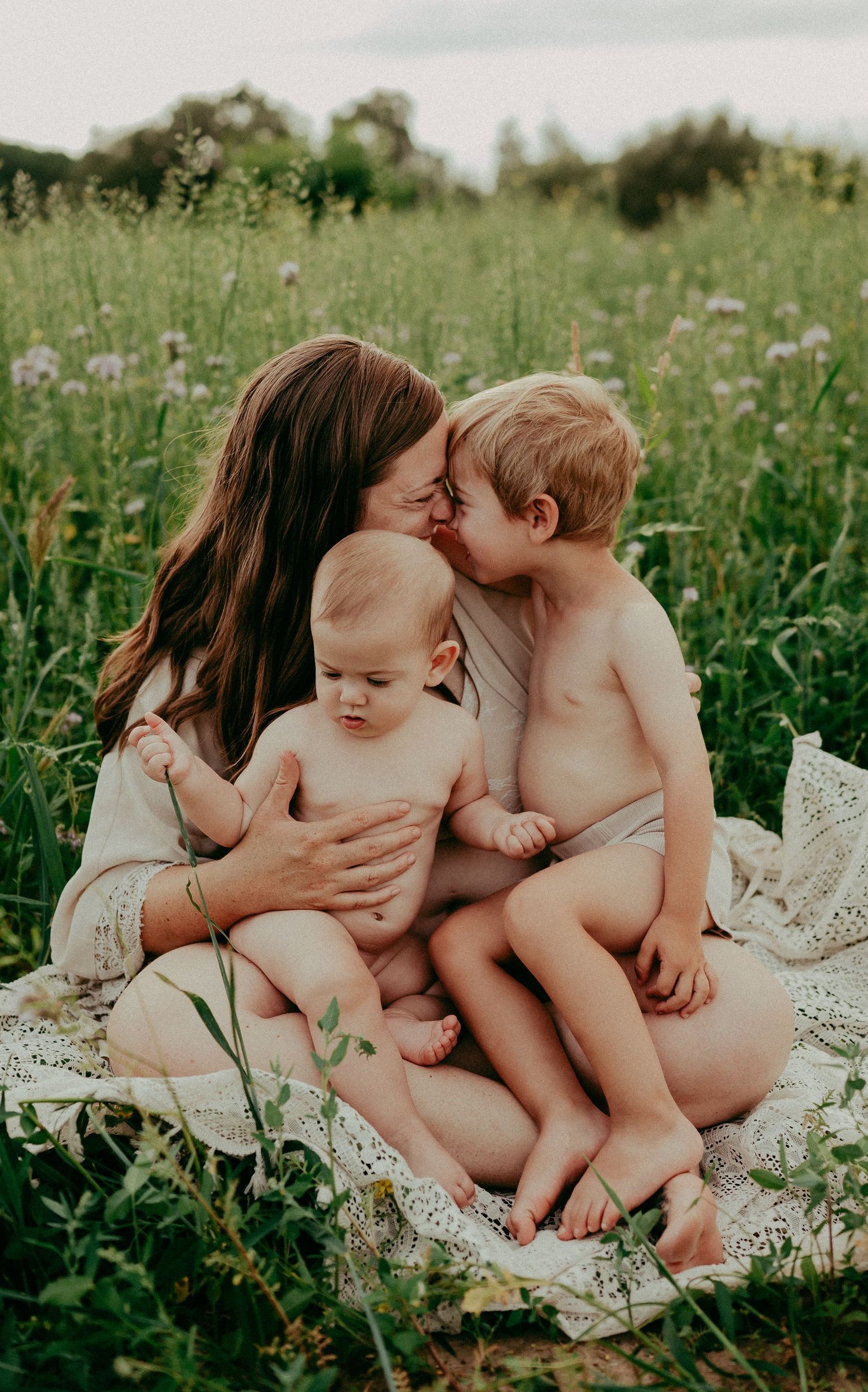A tender moment shared on a blanket in a wildflower meadow during summer.