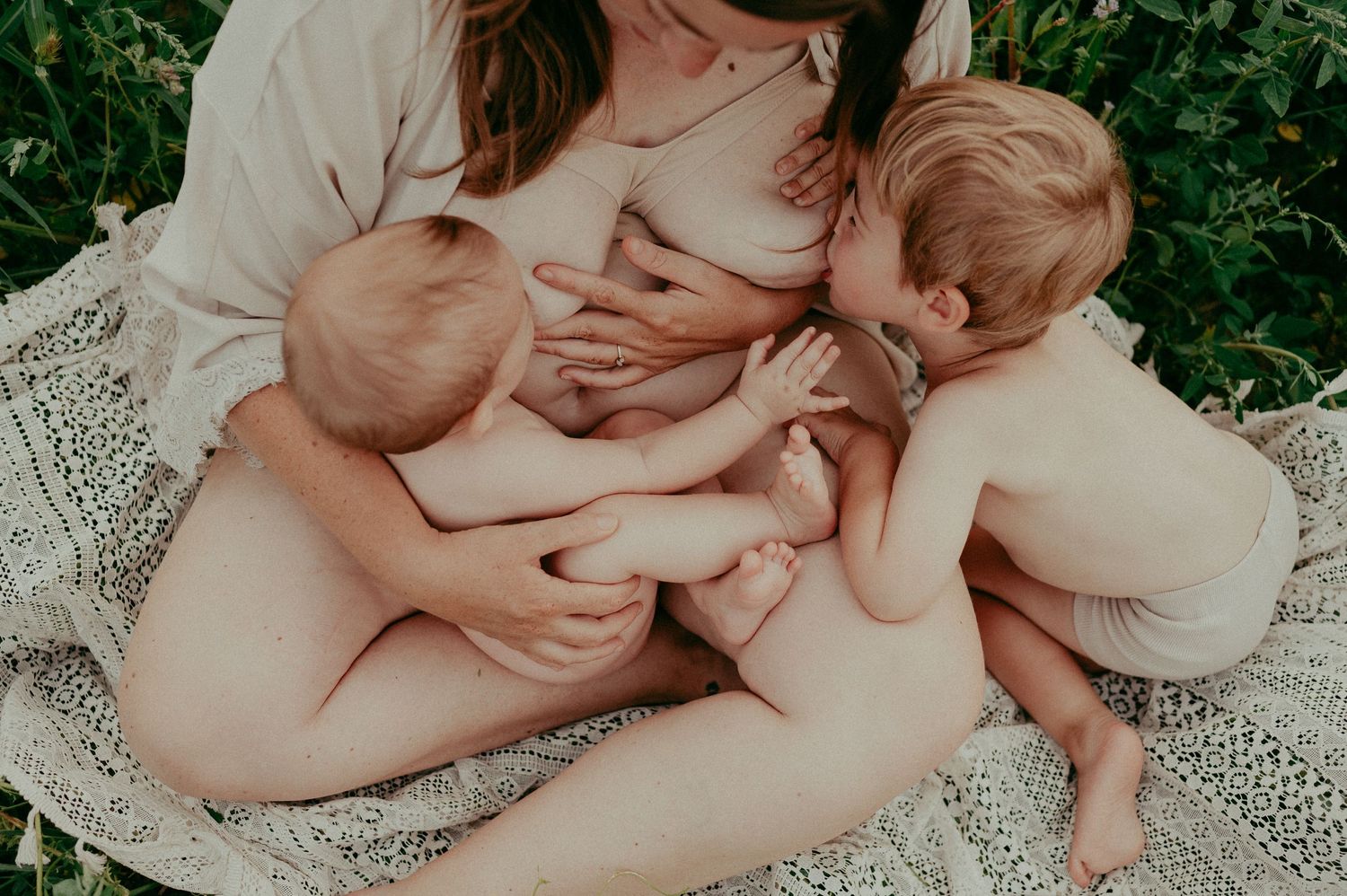 An intimate family moment captured on a lace blanket in a sunlit meadow.