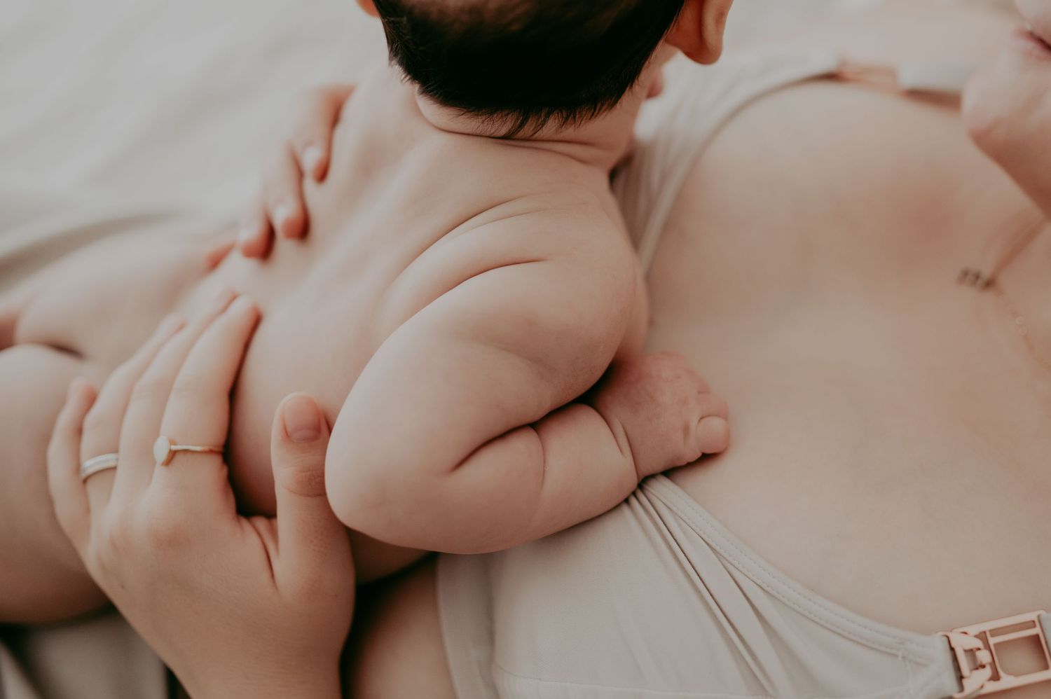 Close-up view of a baby's bare skin and diaper against soft fabric.