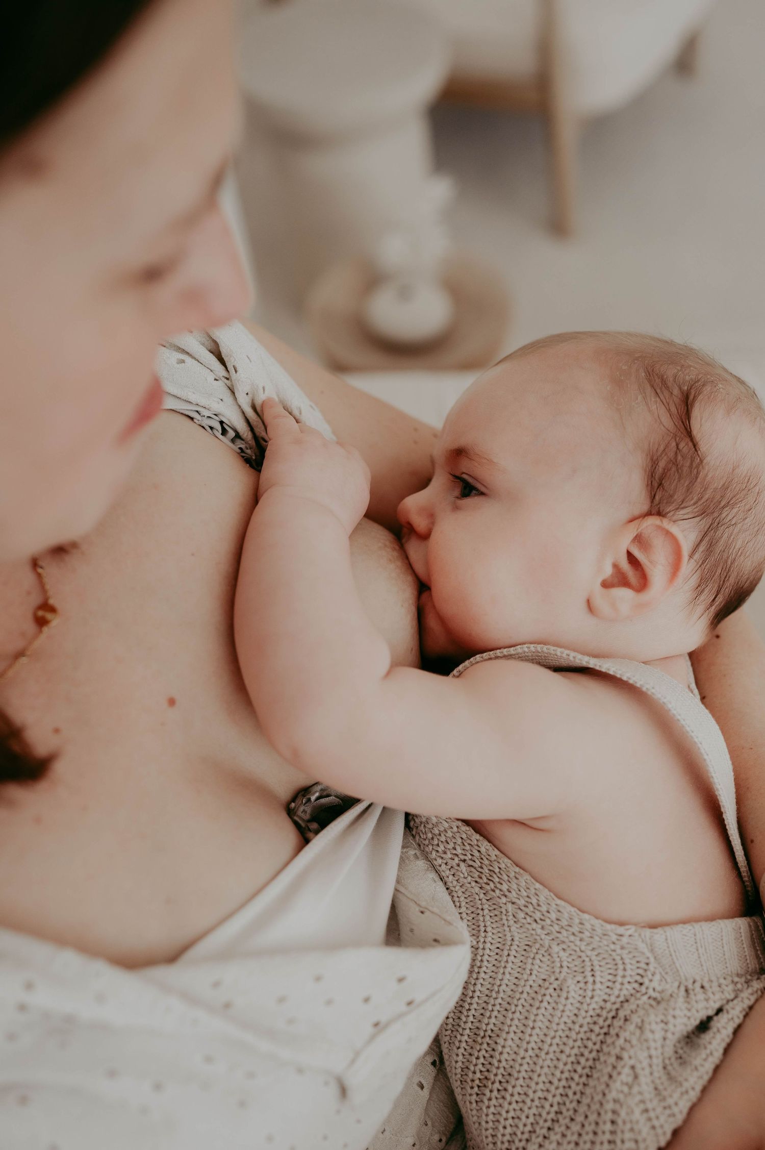 Close-up of tender moment between parent and baby in white knit clothing.