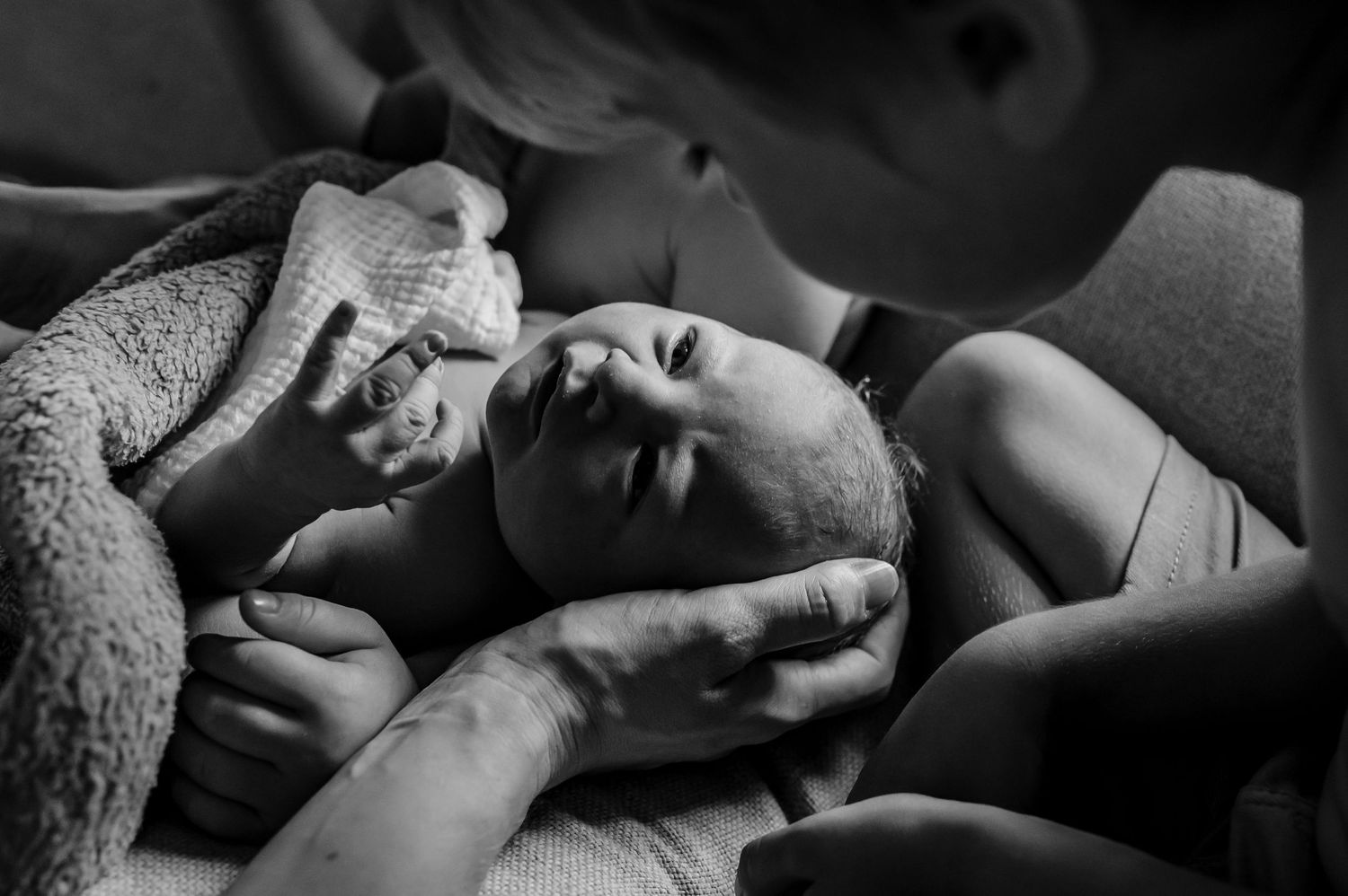 Intimate black and white photograph capturing tender moment of people resting together under blanket.