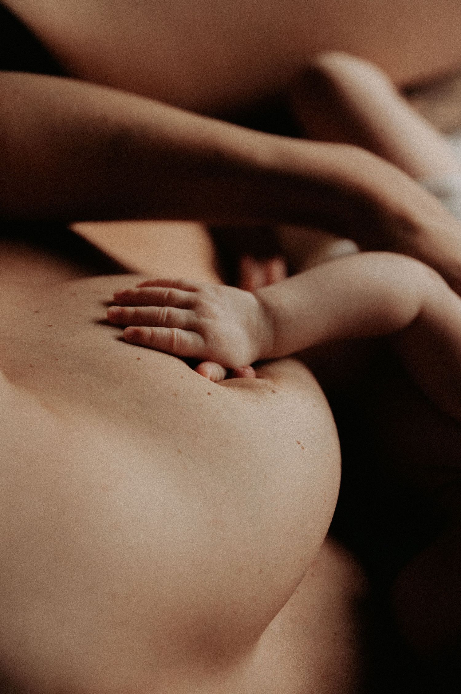 Close-up massage therapy treatment showing hands working on bare skin in warm, sepia-toned lighting.