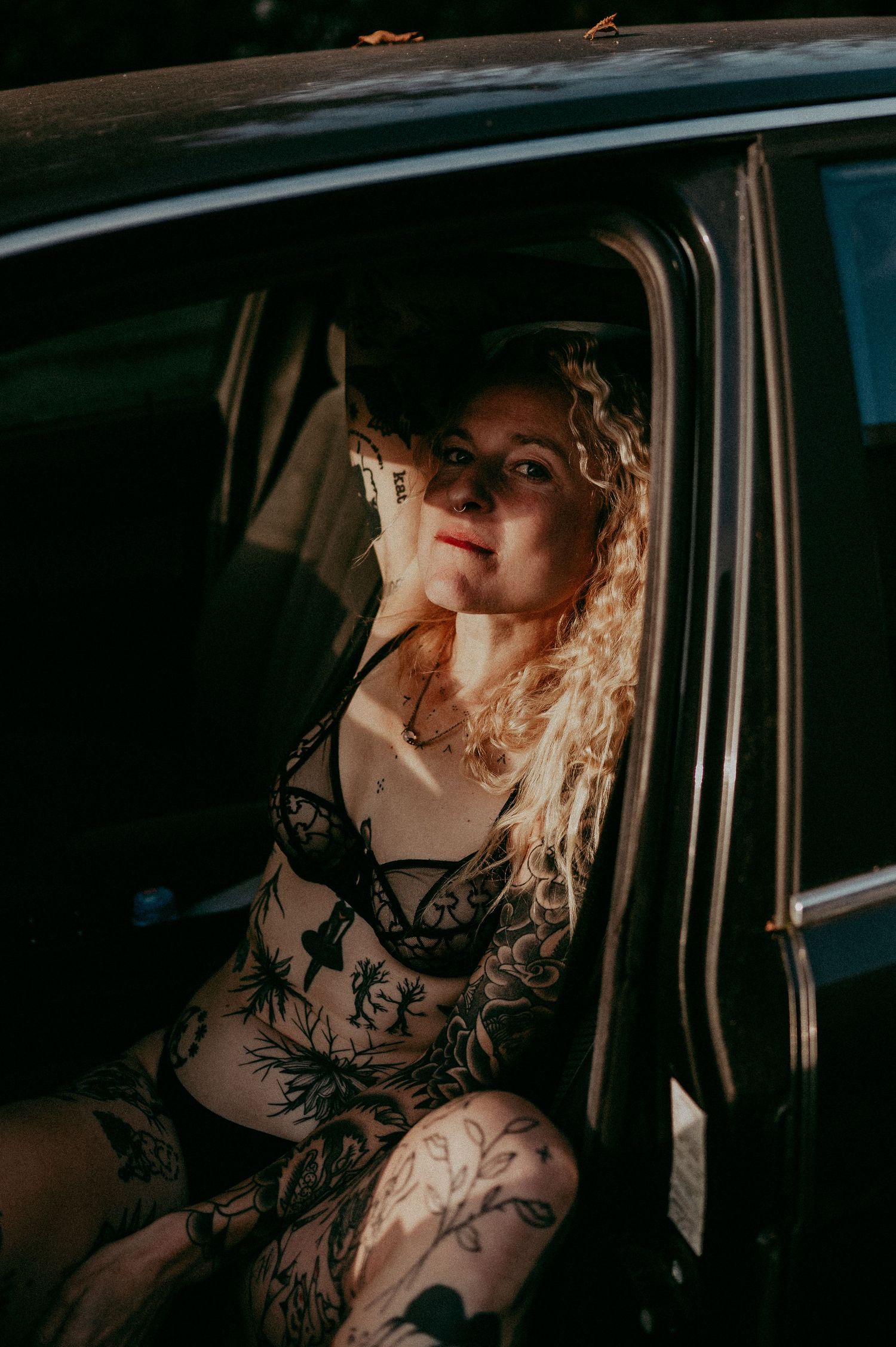 Artistic portrait inside a car with dramatic lighting and shadows.