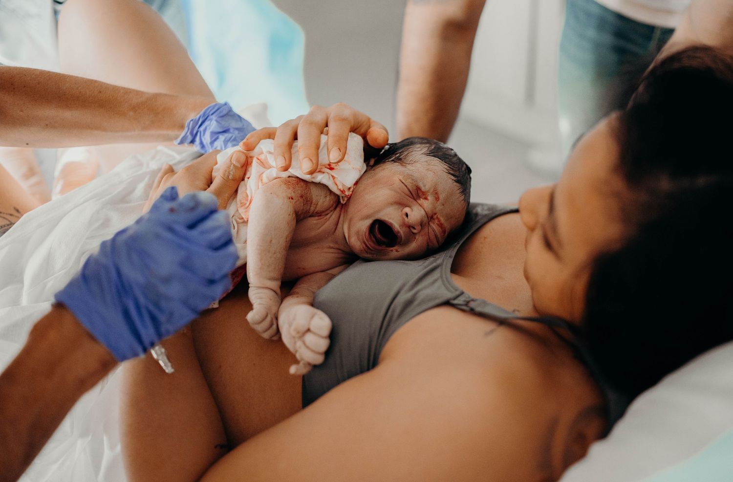 A newborn baby emerges during childbirth as medical staff assists.