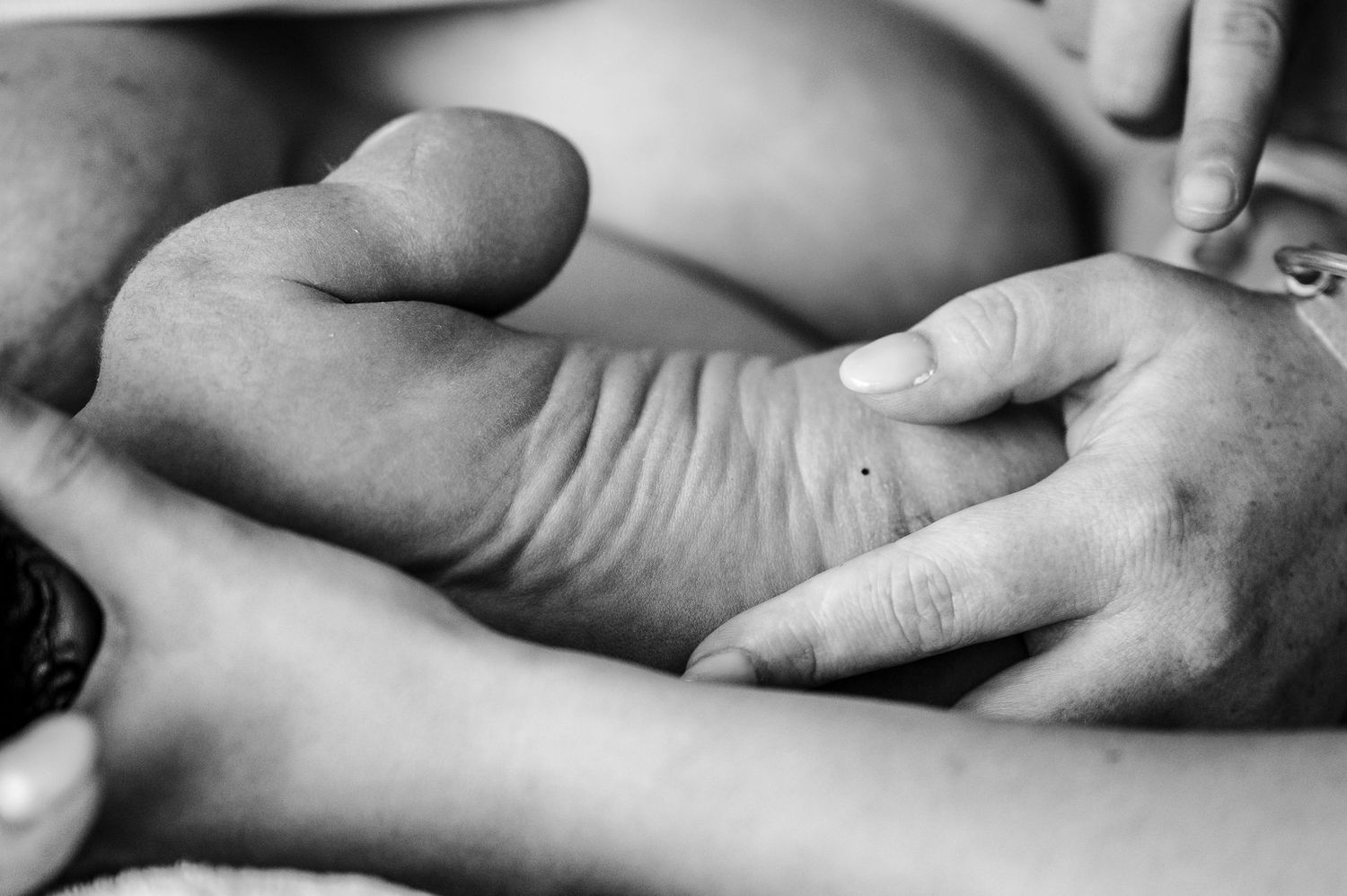 Black and white close-up photo of hands held together in tender embrace showing emotional connection and intimacy.