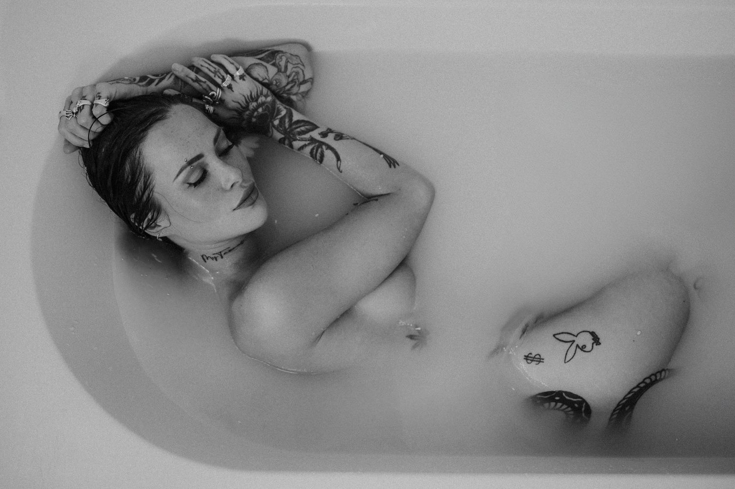 Artistic black and white portrait of a person relaxing in a bathtub.