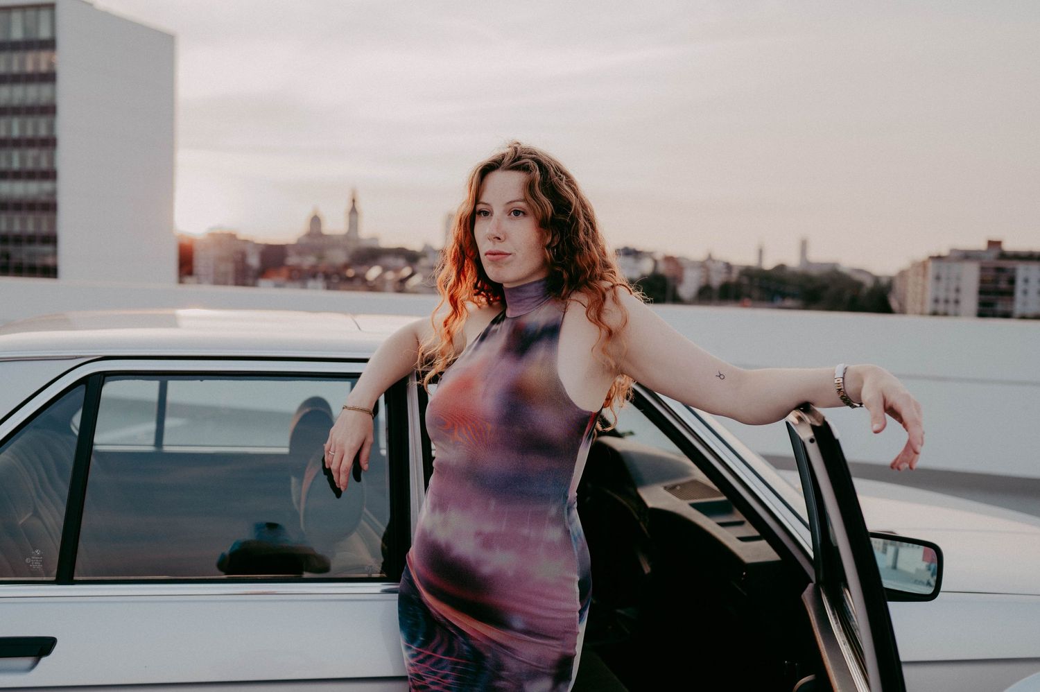 Urban portrait with vintage car and city skyline in warm sunset lighting.