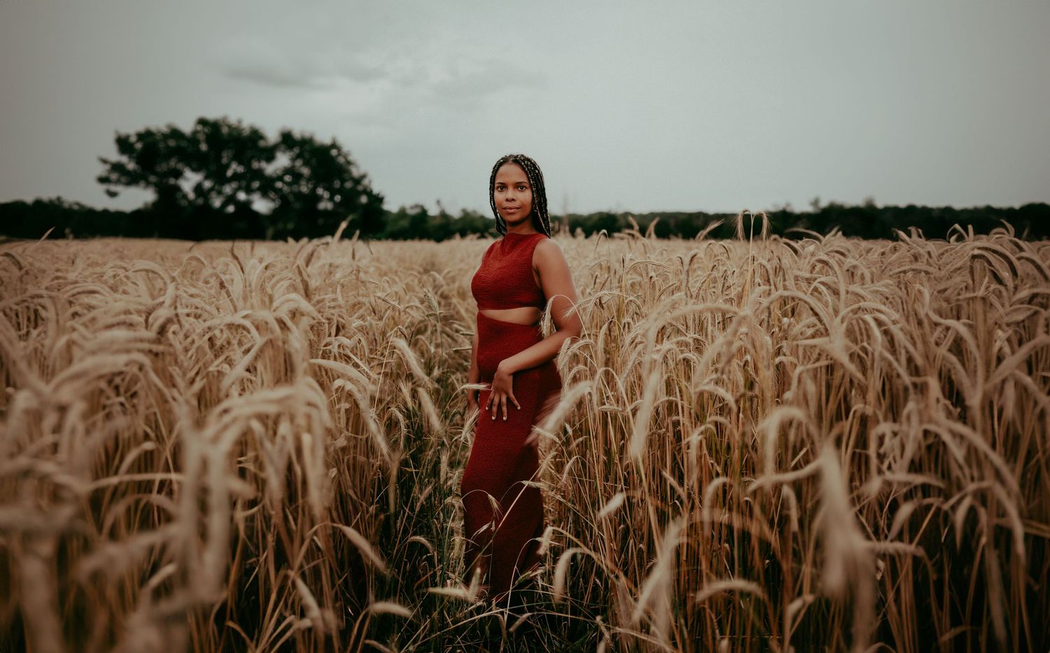 Atmospheric portrait in golden wheat field during overcast evening.