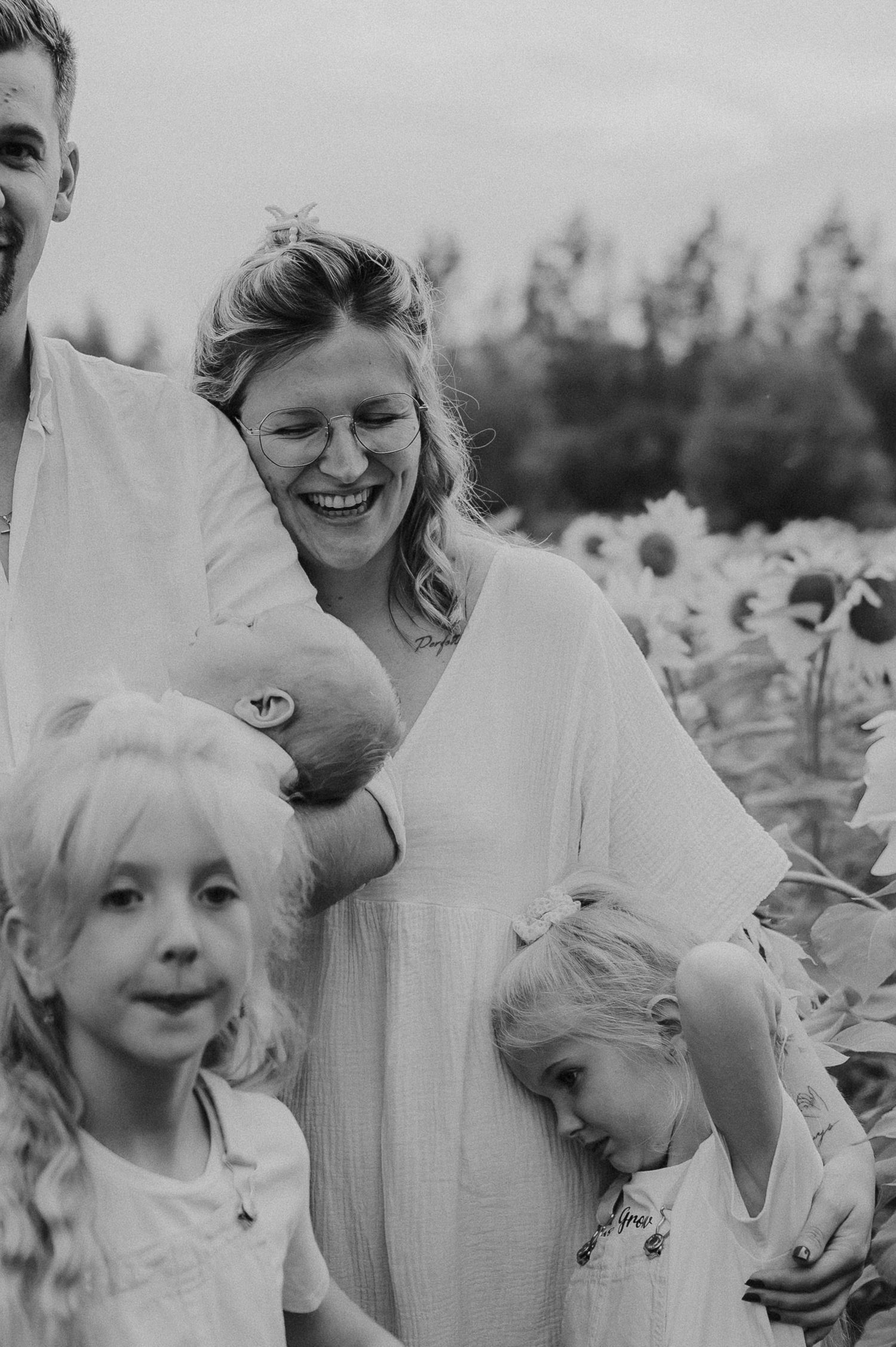Joyful family portrait in black and white among sunflowers.