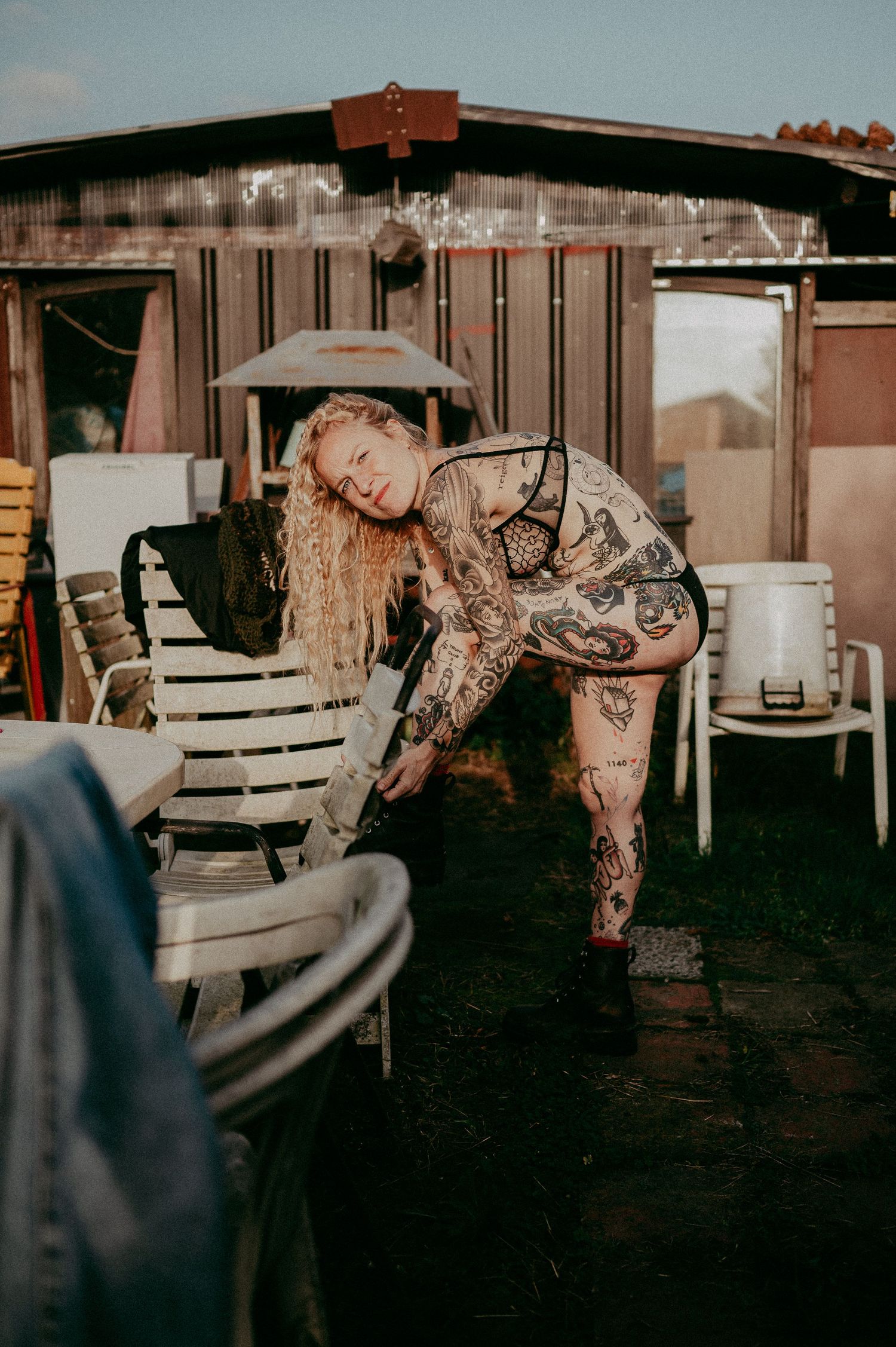 Artistic outdoor portrait in rustic setting with metal building and chairs.