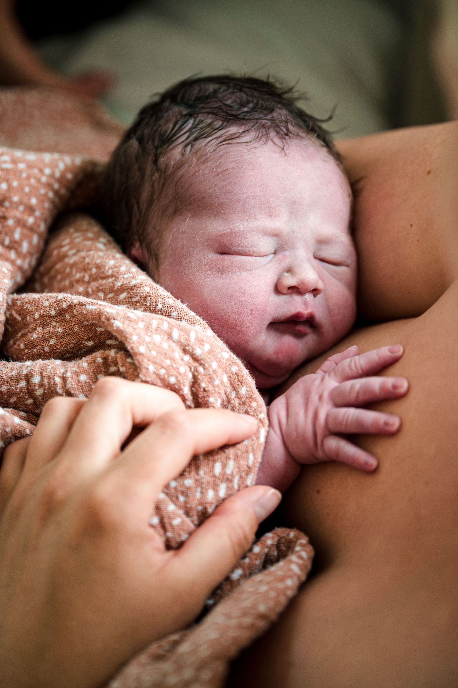 A newborn baby sleeps peacefully while being comforted by gentle hands in a touching series of photographs.