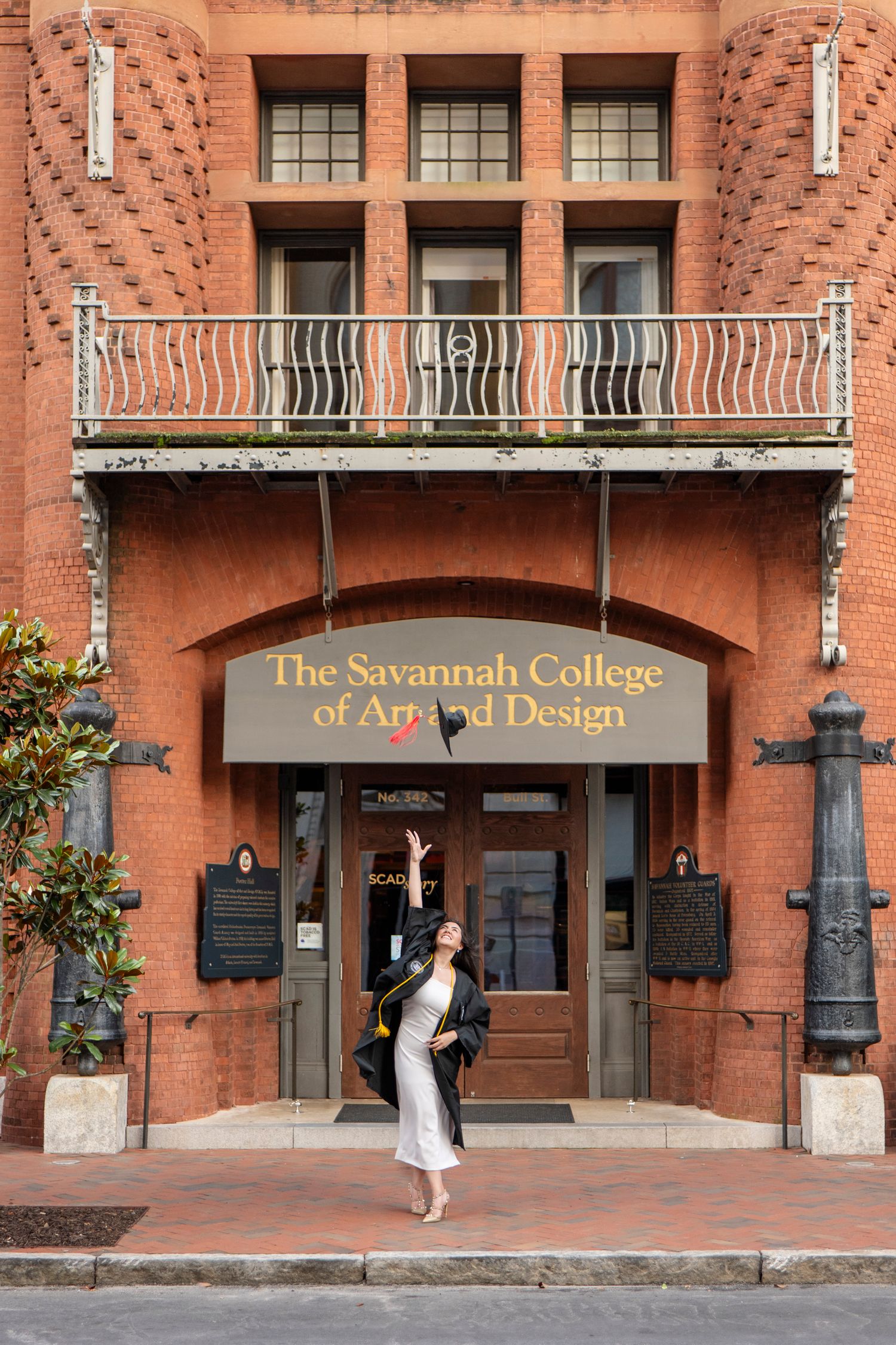 The historic red brick entrance to Savannah College of Art and Design with an ornate balcony and white sign above the doors.