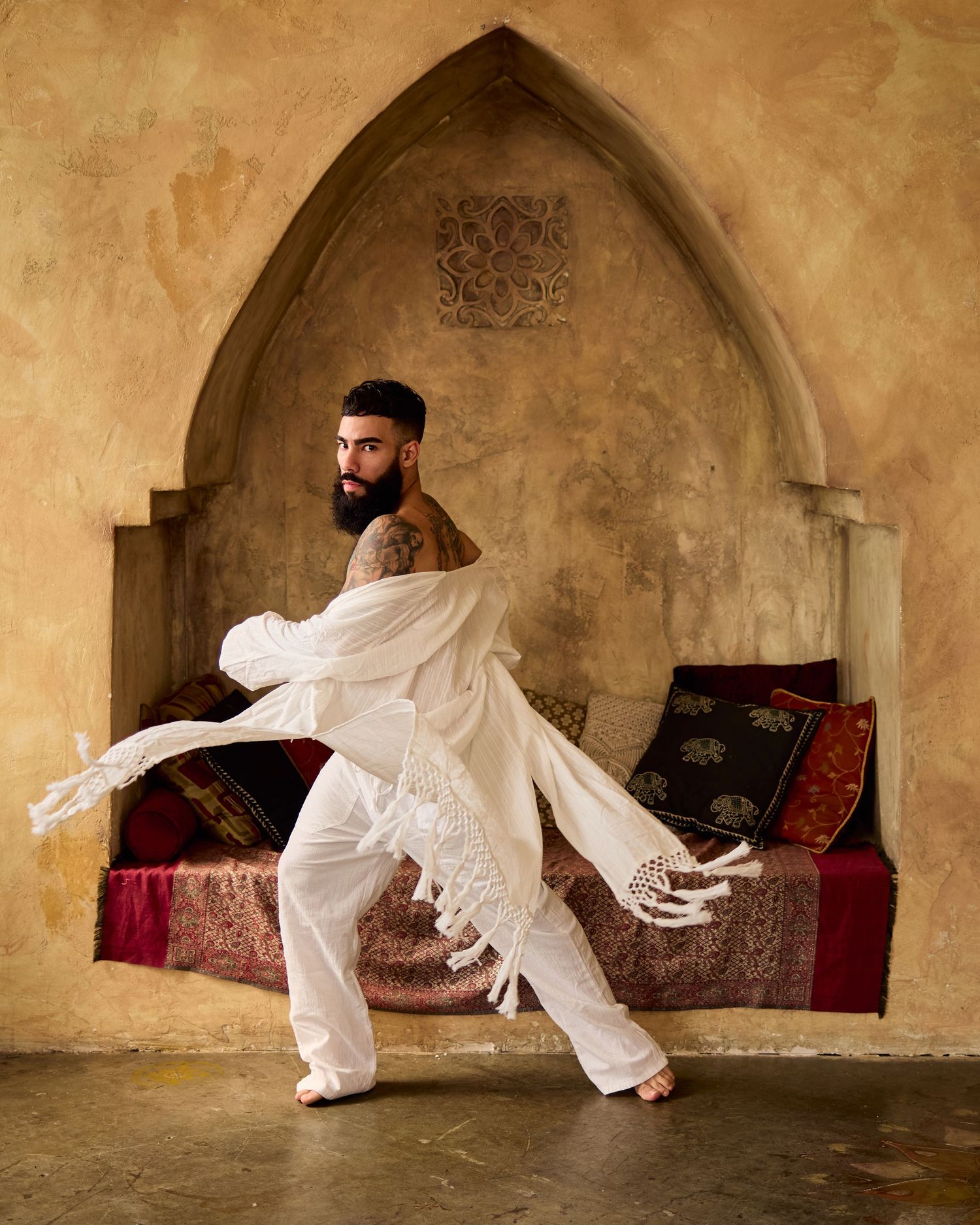 Dynamic movement sequence in white clothing within arched Middle Eastern architectural setting.